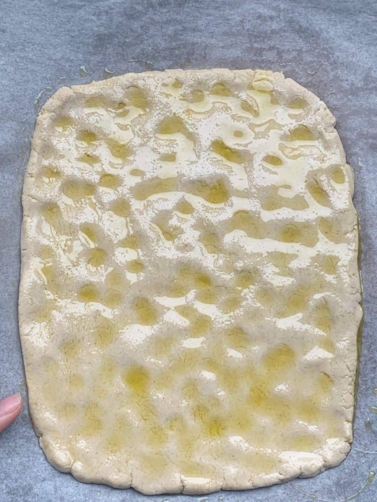 rectangular flatbread dough drizzled with olive oil with indentations