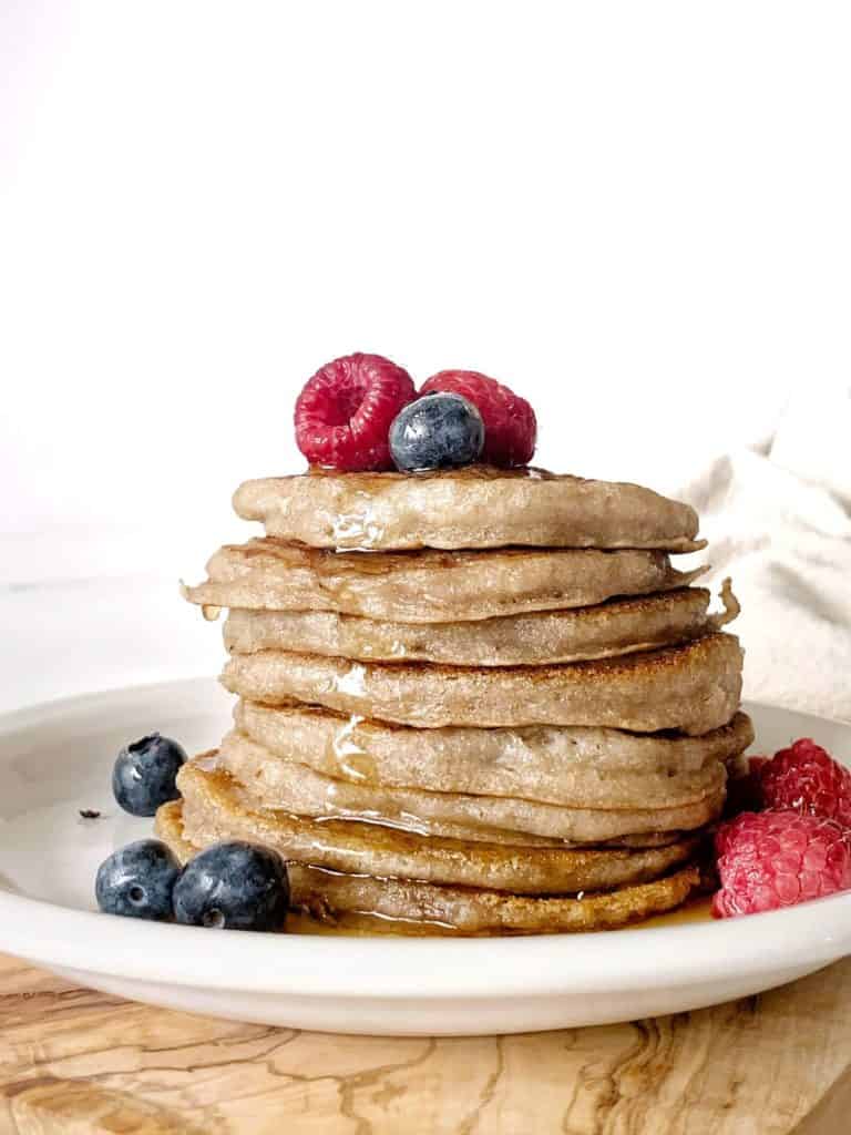Stack of AIP sourdough pancakes (paleo, vegan) with blueberries, raspberries and maple syrup 