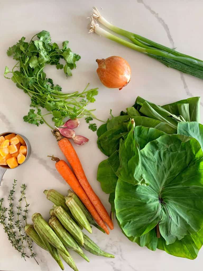 Ingredients for AIP Trinidadian Callaloo soup including okra, fresh thyme, carrots, dasheen leaves, onion, green onions, cilantro and butternut squash