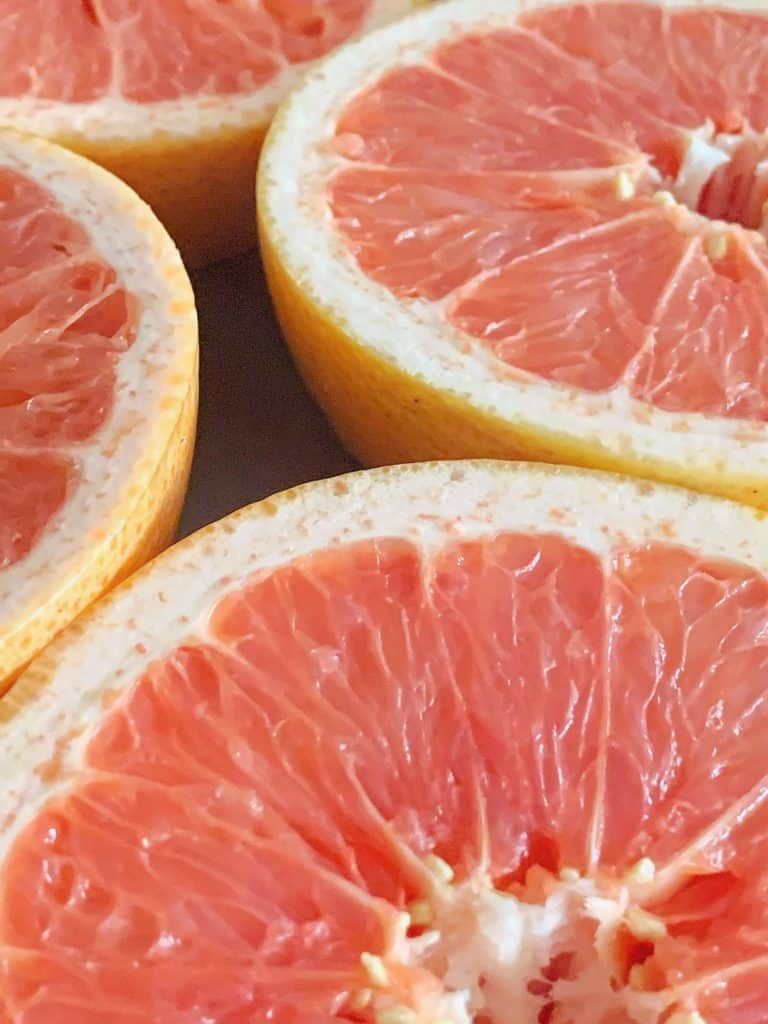 close up shot of four grapefruits cut in half 
