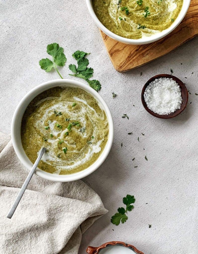 Two bowls of AIP Trinidadian Callaloo Soup (paleo, vegan) topped with coconut milk and herbs.