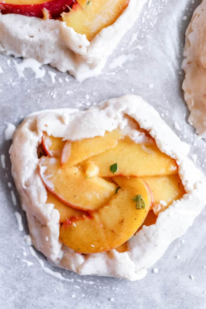 one closeup shot of an unbaked peach galette on a piece of white parchment paper