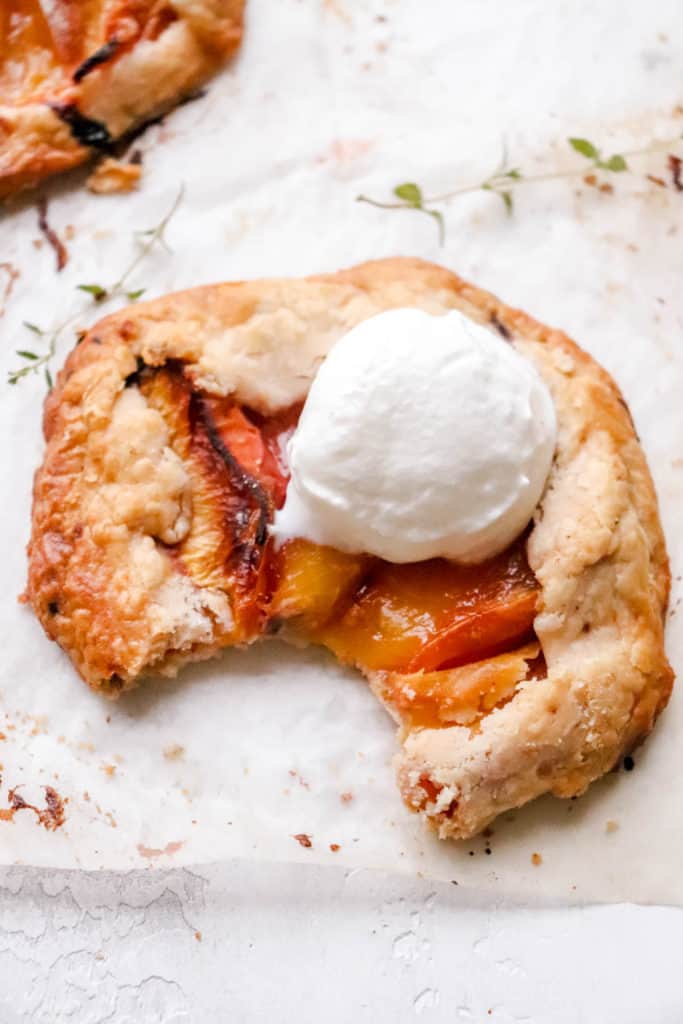 One peach thyme galette with a bite missing and a dollop of yogurt