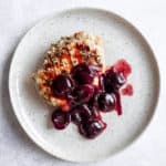 One Grilled Pork Chop with Cherry Compote on a beige plate