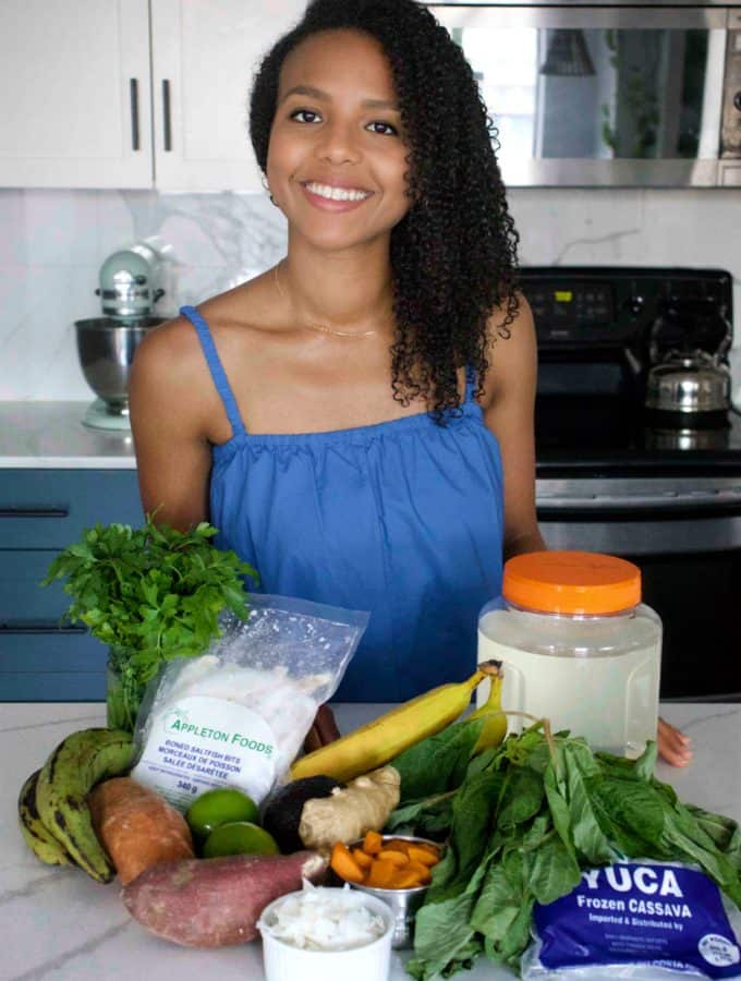 woman in behind a kitchen counter with an assortment of dried ingredients and vegetables on the countertop