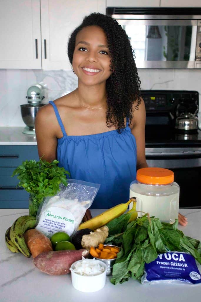 woman in behind a kitchen counter with an assortment of dried ingredients and vegetables on the countertop