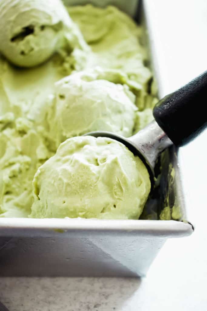 close up shot of loaf pan with matcha ice cream and an ice cream scoop