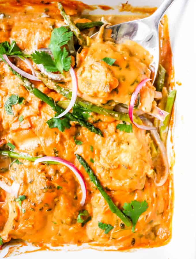 white baking dish with haddock in sweet potato sauce with asparagus and cilantro