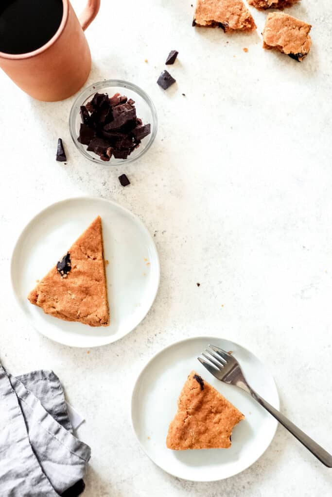 two triangular slices of sweet potato cookie bar with scattered carob chips and a mug of coffee
