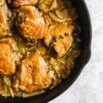 cast iron pan with chicken thighs, apples and fresh thyme