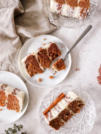 four slices of apple spice cake on white plates and crystal saucers with a light brown cloth napkin