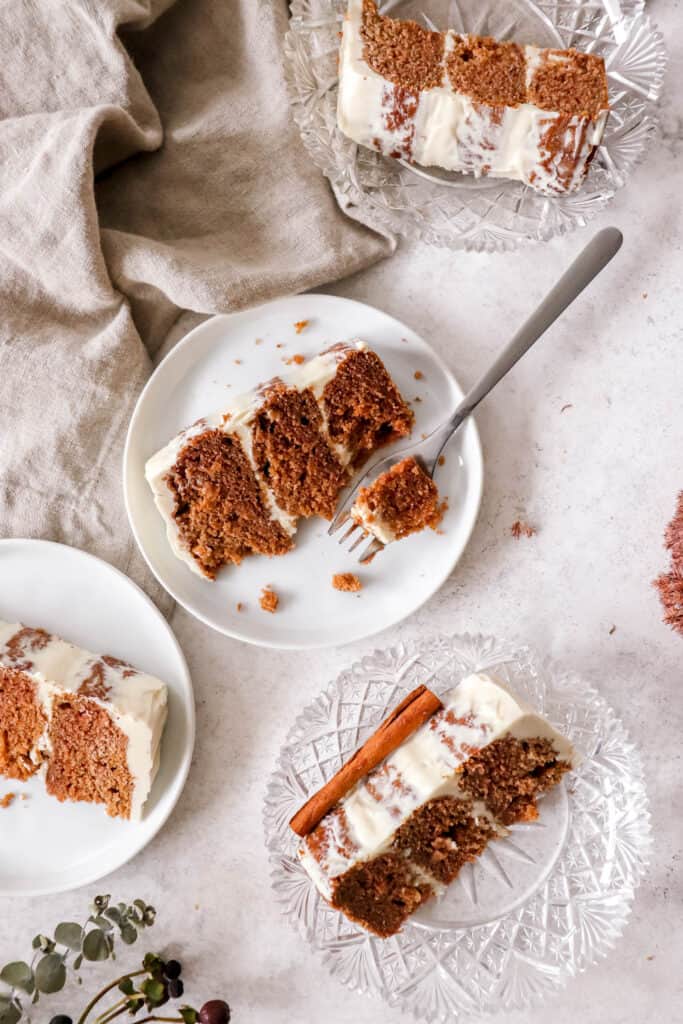 four slices of apple spice cake on white plates and crystal saucers with a light brown cloth napkin