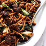 close up of beef, noodles, bok choy and basil with serving spoon