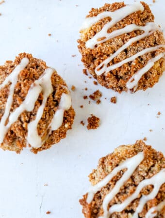 three cinnamon streusel muffins with coconut glaze drizzled on top