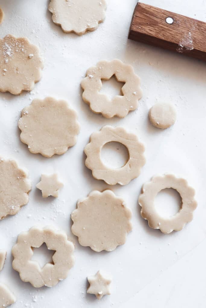 cut outs of linzer cookies with a pastry cutter on a piece of white parchment paper