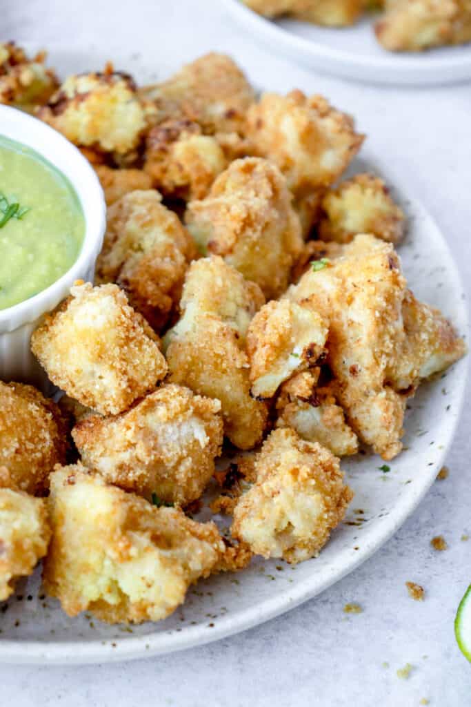 speckled plate with crispy cauliflower bites with a cilantro lime sauce