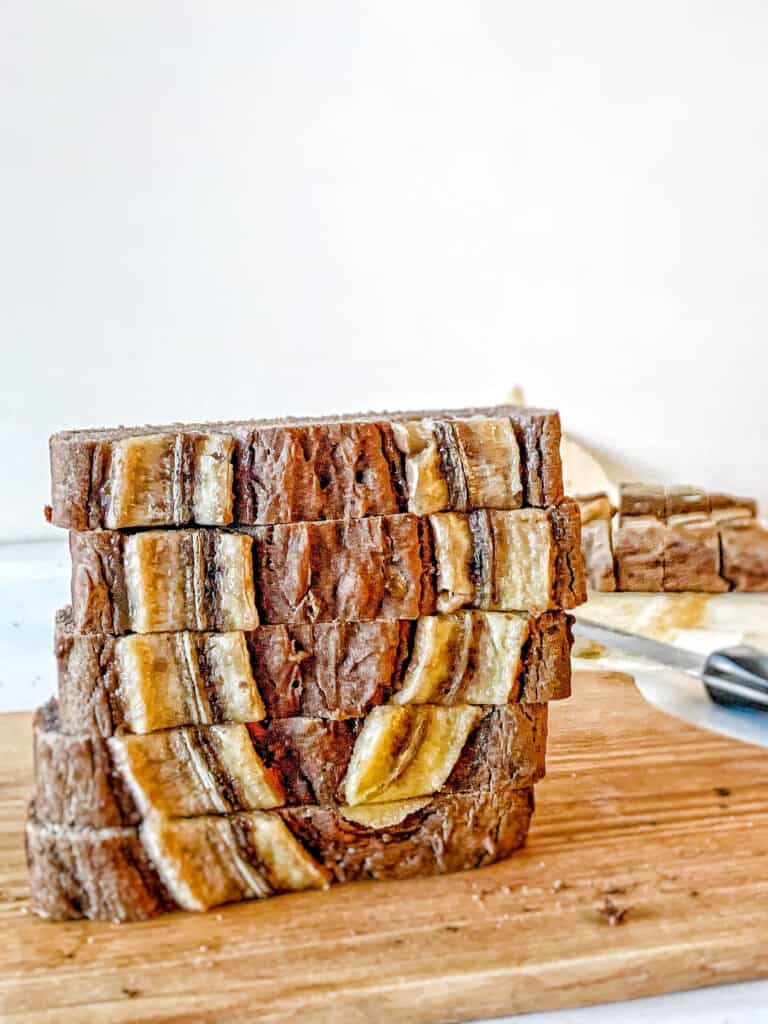 wooden cutting board with sliced banana bread stacked vertically