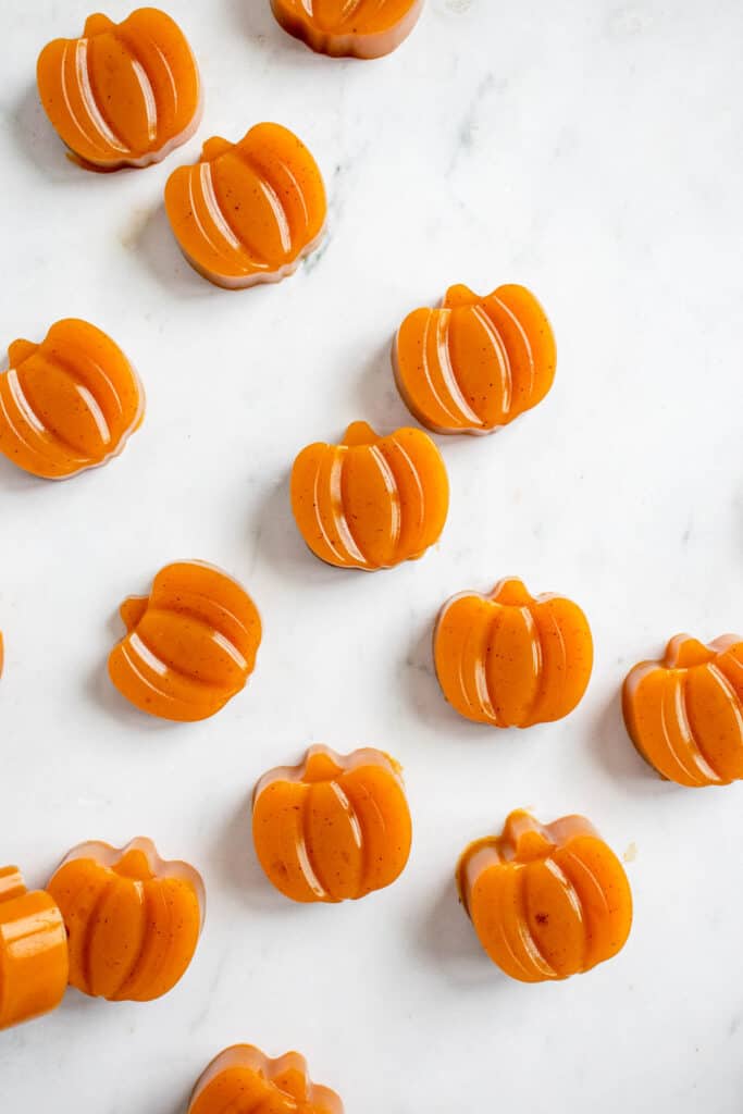 overhead shot of pumpkin shaped orange gummies laid out on a white and grey marbled background