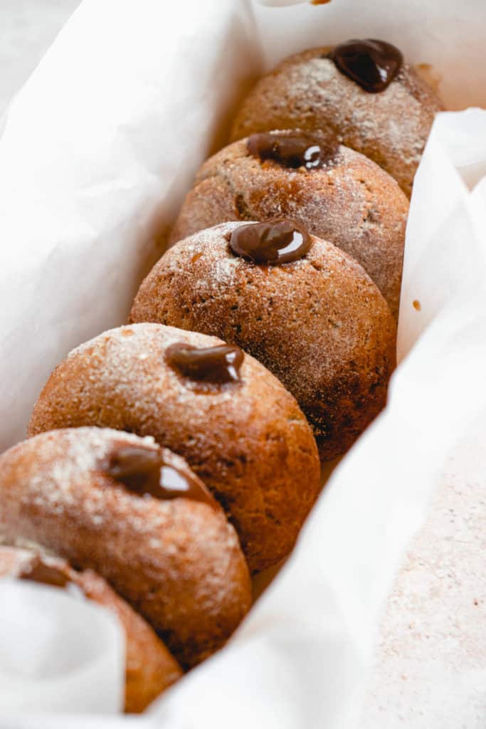 parchment lined bread pan filled with six mini donuts stuffed with salted caramel filling