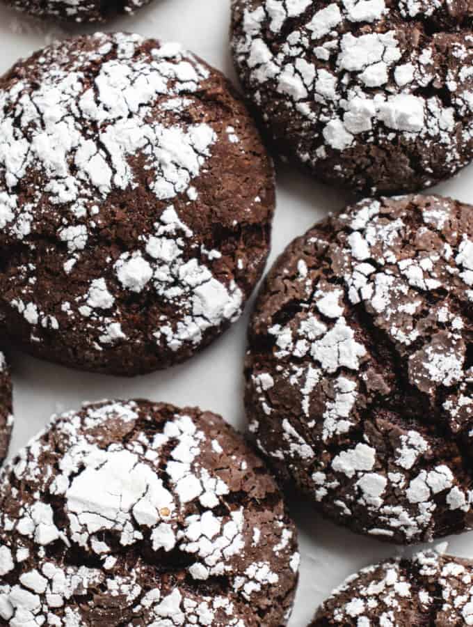 overhead shot of chocolate crinkle cookies on a white piece of parchment paper