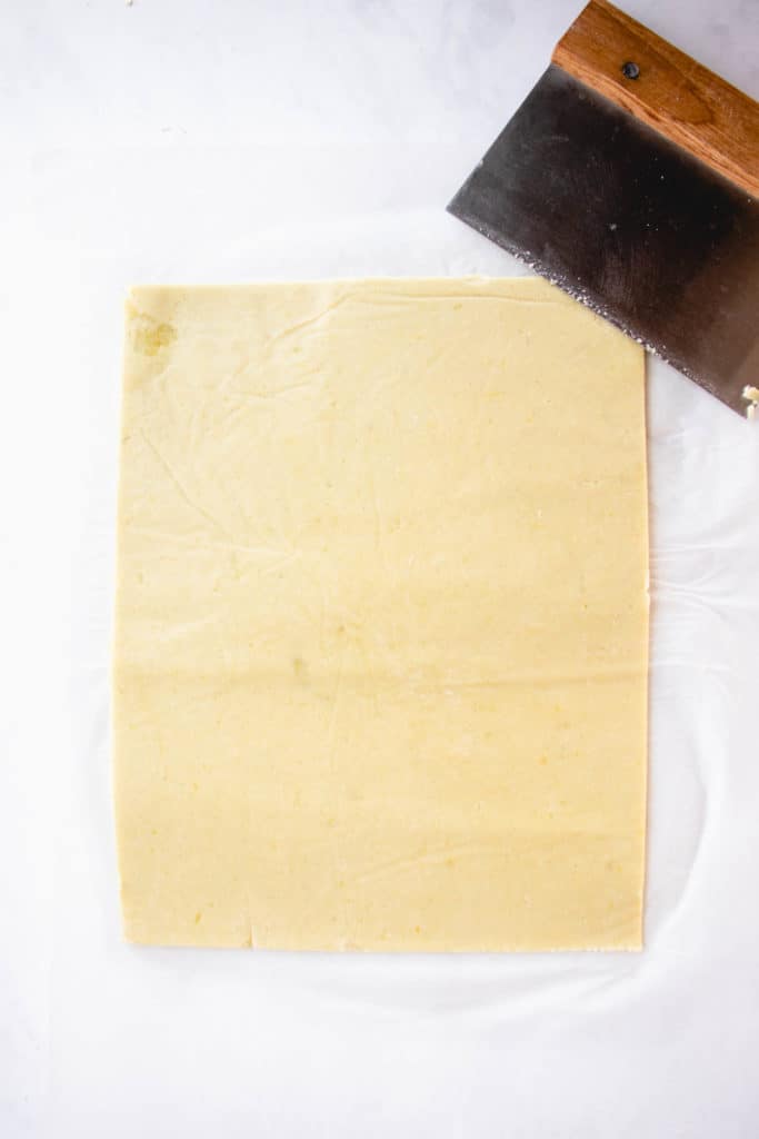 sweet potato and cassava flour dough rolled out into a rectangle cut with a bench scraper shown in the top right of the image