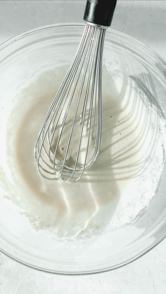 clear glass bowl with batter for fish and a whisk inside the batter