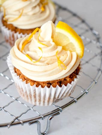 close up shot of one paleo lemon olive oil cupcake with frosting and garnish