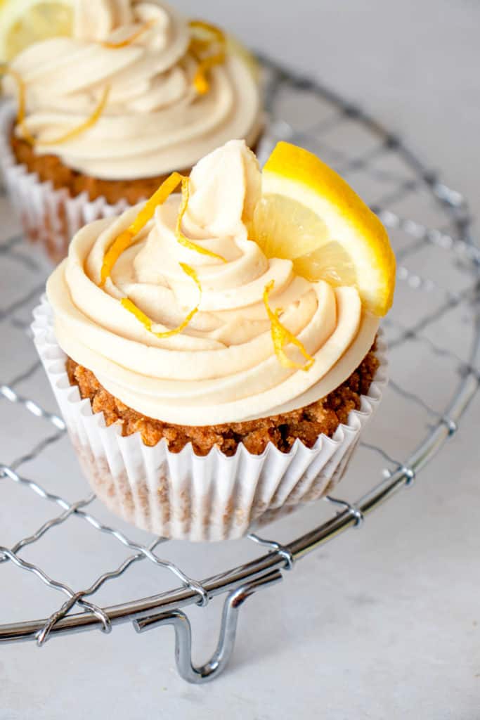 close up shot of a paleo lemon olive oil cupcake with frosting and garnish