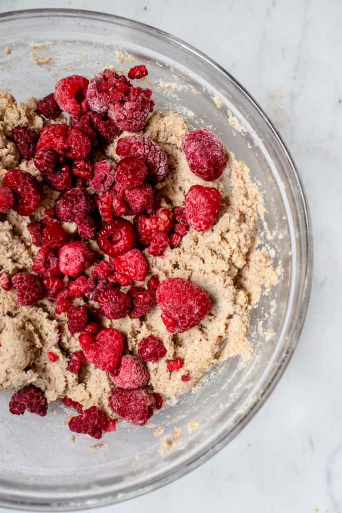 overhead shot of large glass bowl with raspberry lemon loaf cake batter sprinkled with raspberries