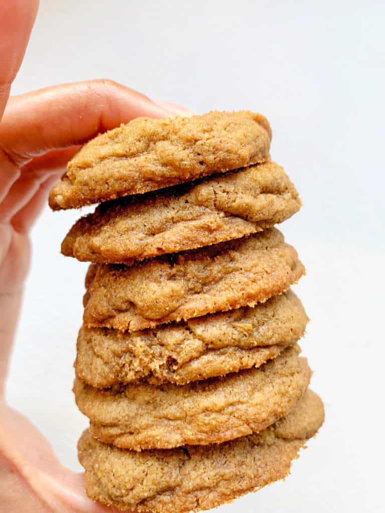 hand holding stack of six gingersnaps against a white backdrop