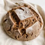 fresh loaf of aip sourdough bread on pale yellow tea towel