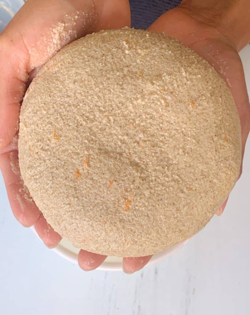 brown hands holding round shaped dough