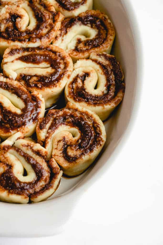 overhead shot of a white oval-shaped dish filled with cinnamon rolls ready for the oven