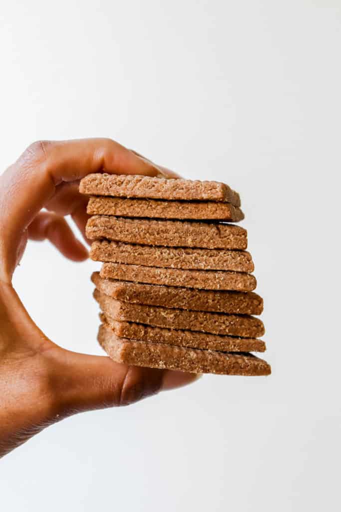 hand holding stack of grain free paleo/aip spiced shortbread cookies against a white backdrop