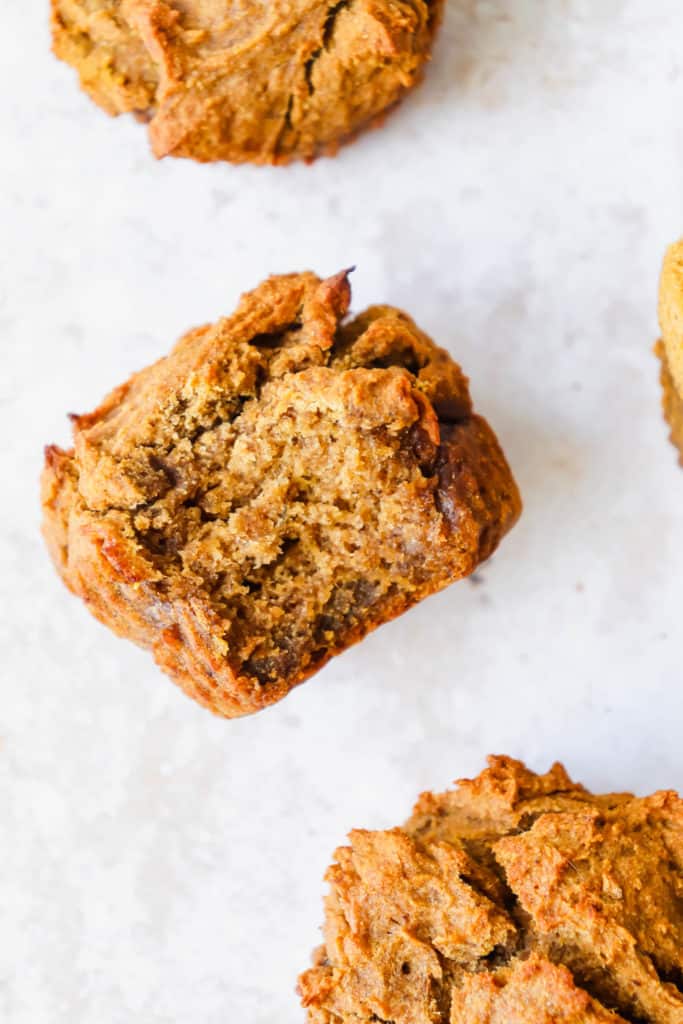 four pumpkin banana muffins with a bite taken out of one of them