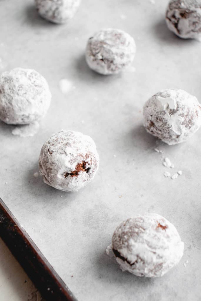 balls of chocolate crinkle cookie dough rolled in arrowroot starch on a parchment-lined baking tray