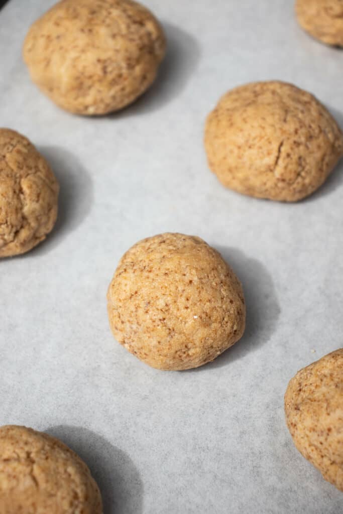 Balls of dairy-free, paleo, AIP snickerdoodle cookie dough on a parchment-lined baking sheet