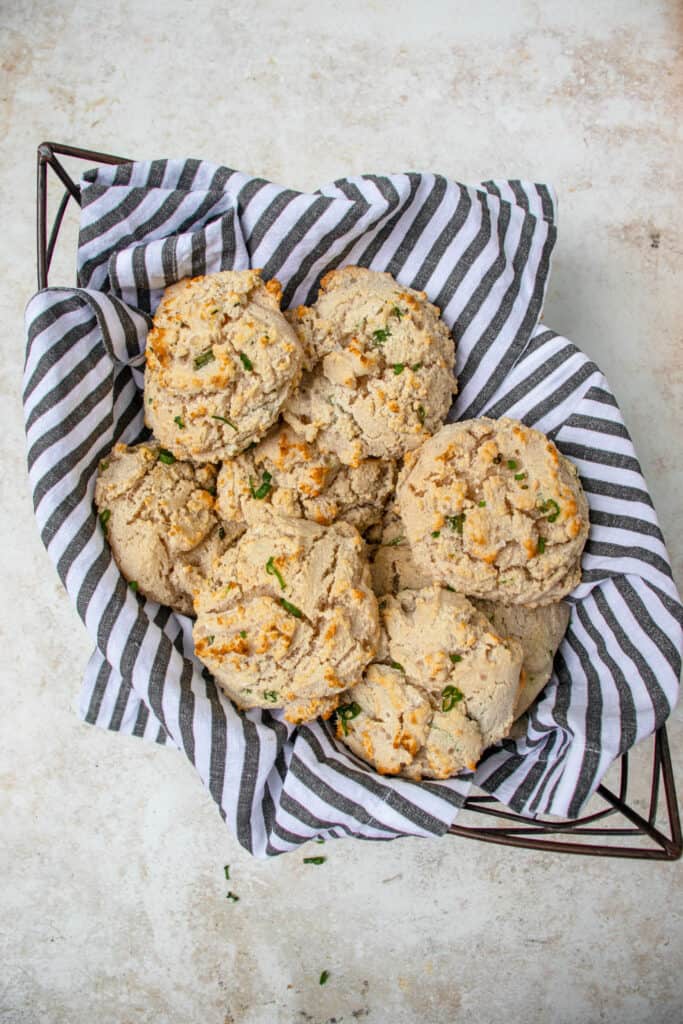 Eight Vegan Gluten-Free Drop Biscuits nestled in a tea towel-lined metal bread basket