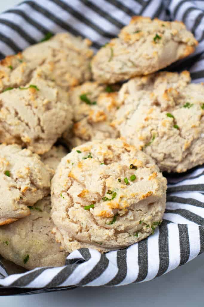easy vegan gluten-free biscuits with chives in a bread basket lined with a striped tea towel