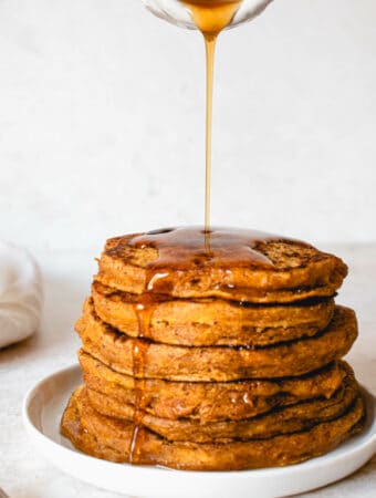 stack of vegan paleo pumpkin spice pancakes with maple syrup drizzled on top