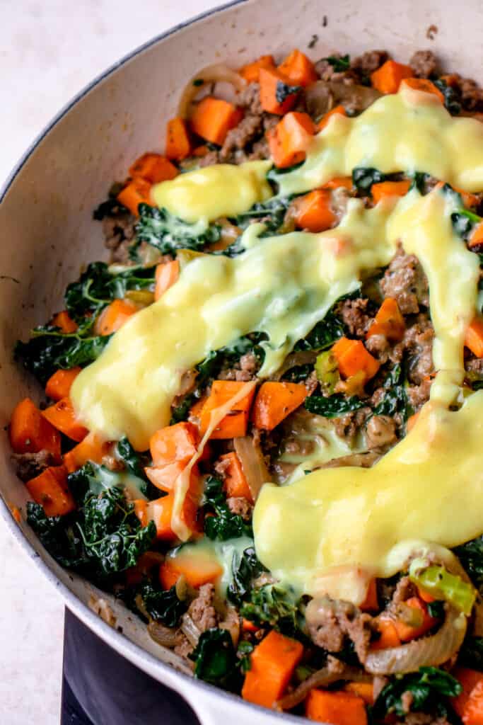 process shot with casserole ingredients including ground beef, cubed orange sweet potatoes, kale and dairy free AIP cheese sauce
