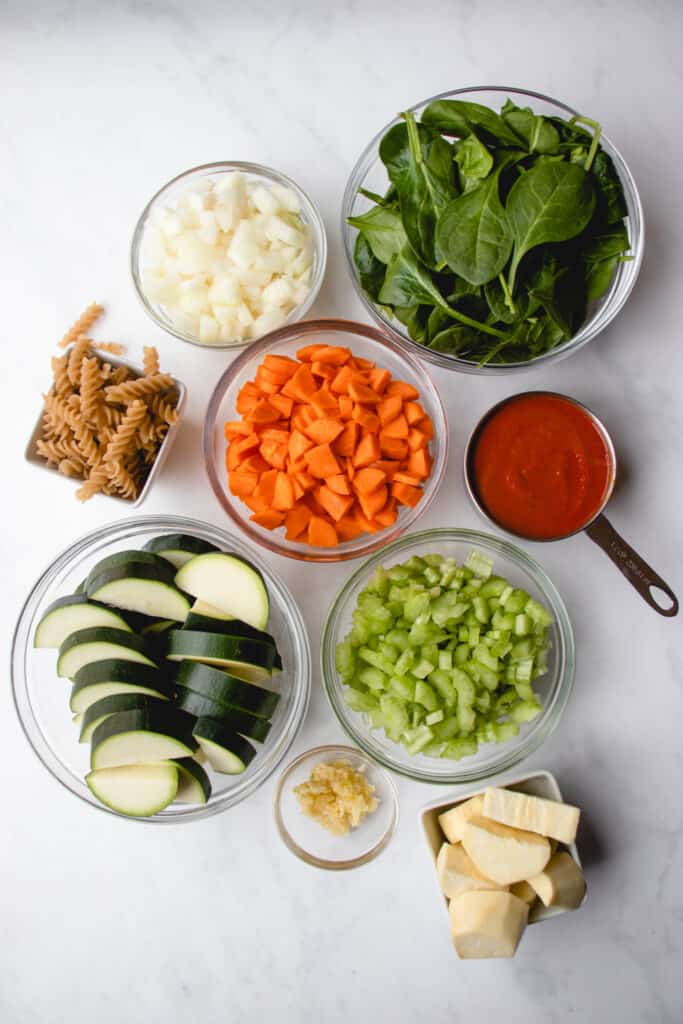 Mise en place of vegetables, nomato sauce and grain-free pasta.