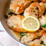 Gluten Free Chicken Piccata (AIP, Paleo) garnished with lemons and parsley in a skillet.
