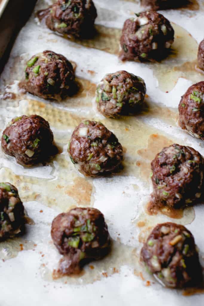 Cooked beef meatballs on baking tray.