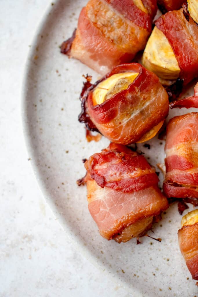 overhead shot of beige speckled plate with slices of sweet baked plantains wrapped in bacon