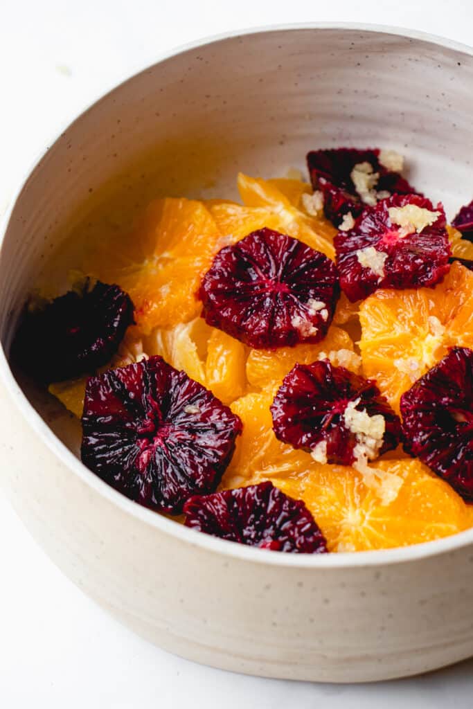 Mixed orange slices with garlic in a bowl