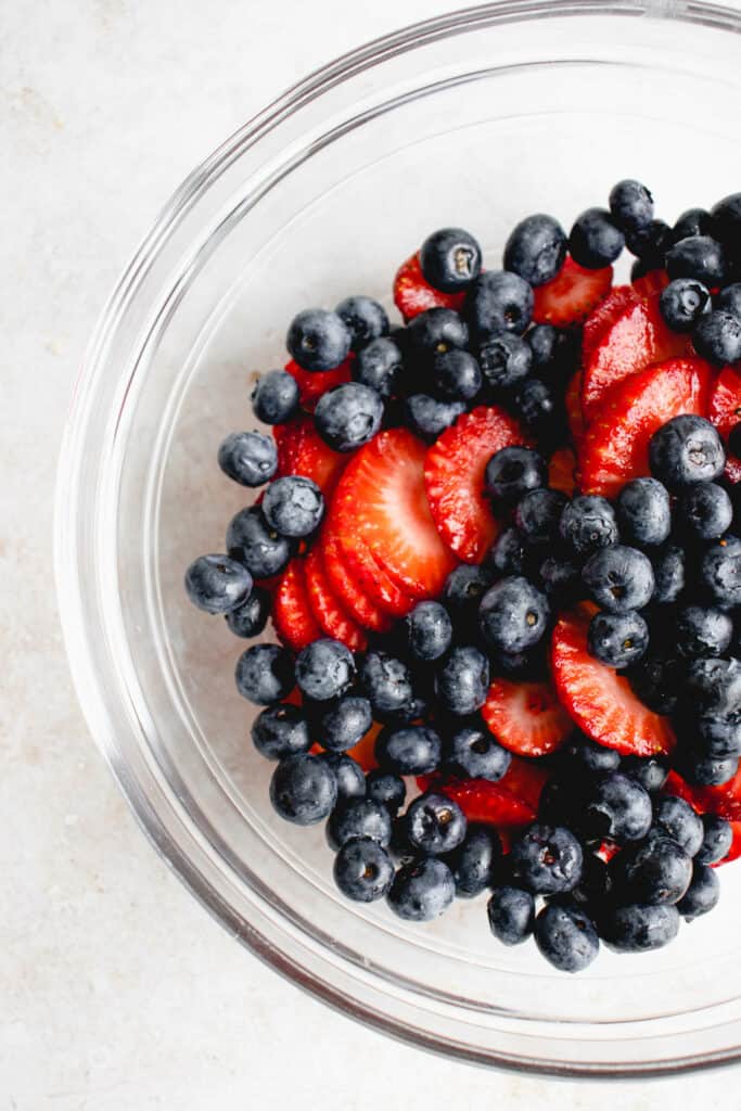 Glass bowl with blueberries and sliced strawberries