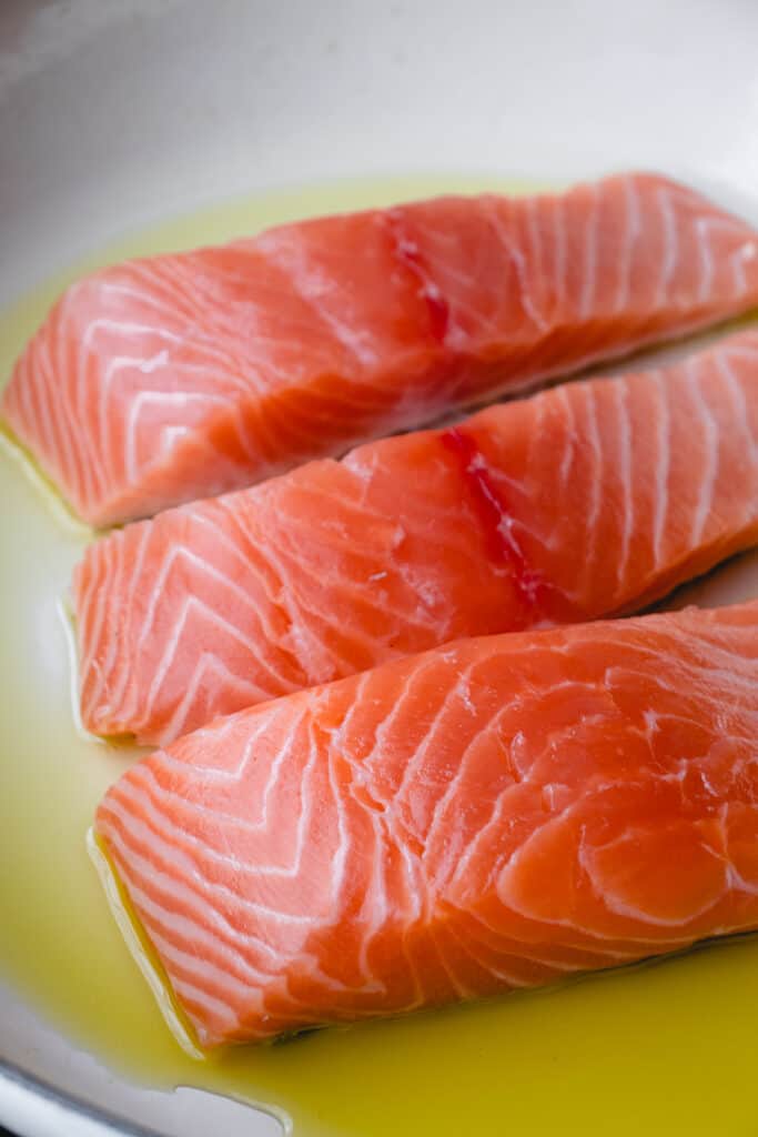 Salmon filets in a pan with olive oil.