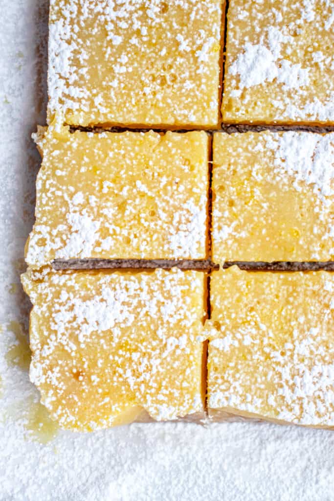 Parchment paper with six cut lemon squares dusted with arrowroot starch.