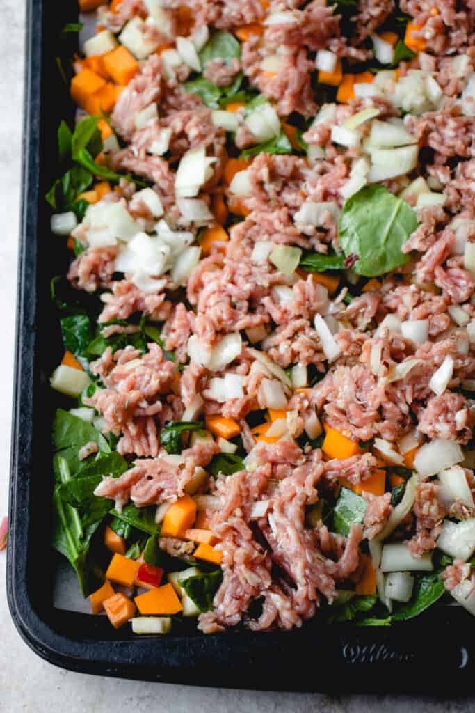 Seasoned ground meat spread evenly, added to sheet pan